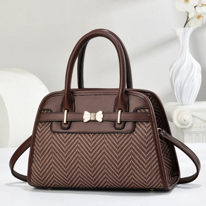 Close-up of brown herringbone woven handbag with golden bow metal buckle detail