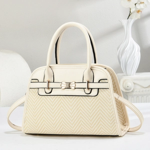 Detail of elegant beige herringbone handbag with golden bow hardware and leather trim