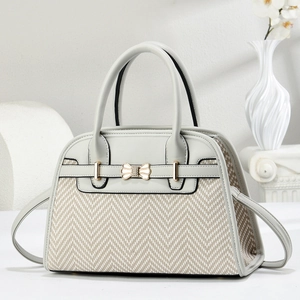 Detail of grey leather and chevron weave handbag with golden bow buckle on a marble column