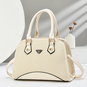 Close-up of beige woven shell bag featuring herringbone pattern and gold hardware