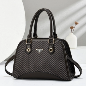 Detail of herringbone pattern texture and metal logo plaque on a brown shell bag