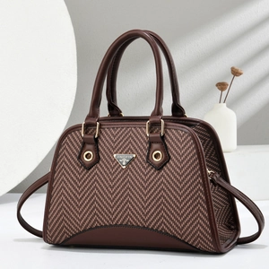 Elegant herringbone shell bag with brown leather trim and golden hardware hand-held