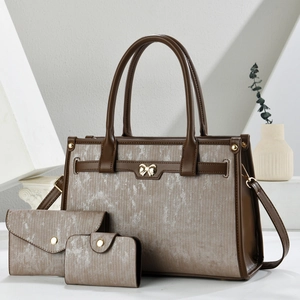 Three-piece tote bag set with striped fabric and brown leather trim in minimalist setting