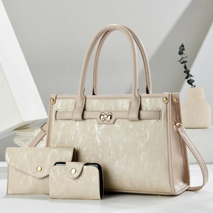 Three-piece beige tote bag set with metallic texture and elegant golden bow hardware