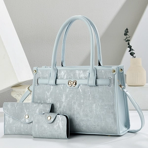 Detailed close-up of light blue textured tote bag 3-piece set with golden bow hardware