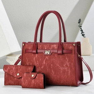 Detailed view of burgundy tote bag set with metallic texture and golden bow decoration