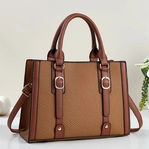 Brown woven tote bag with leather handles and gold buckles on a minimalist background