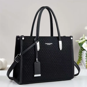 Detail of black woven tote bag featuring leather handles and silver brand logo text