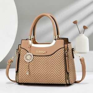 Détail d'un sac à main marron avec texture tressée et logo doré sur le devant
