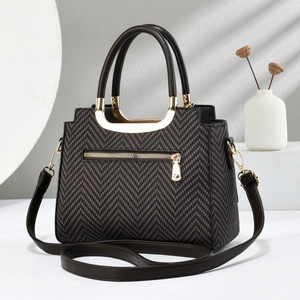Détail du sac à motif chevrons avec ferrures dorées en U et poignée marron