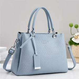 Detail of light blue faux leather handbag with herringbone texture and Fashion Queen text
