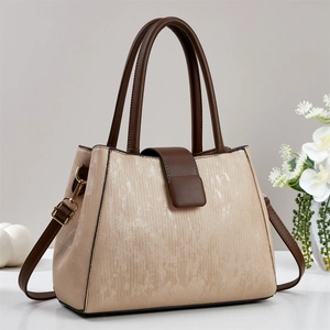 Detail showing high-capacity leather handbag with champagne textured fabric and brown straps