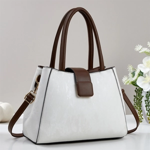 Detail of white leather tote with brown handles and golden hardware on minimal background