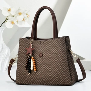 Elegante braune Handtasche mit Fischgrätenmuster und Holzstern-Anhänger auf Display