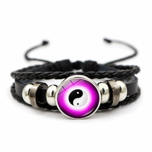 Détail du charm Yin Yang sur bracelet en cuir tressé noir avec des perles argentées
