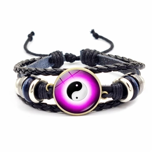 Détail macro du bracelet en cuir tressé à la main avec breloque Yin Yang et perles