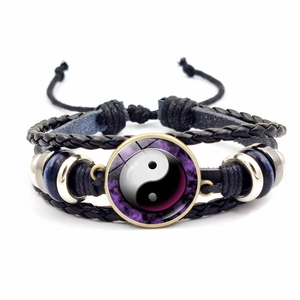 Détail macro du bracelet en cuir tissé main avec breloque en verre Tai Chi Yin Yang