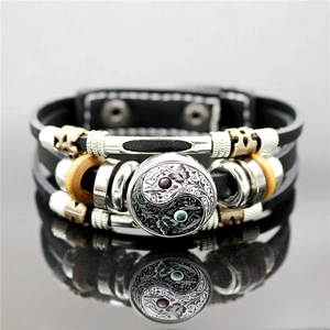 Dettaglio macro del bracciale in pelle Yin Yang con motivi a farfalla e perline in legno