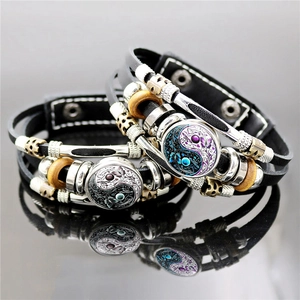Dettaglio macro del bracciale in pelle con farfalla yin yang e motivi floreali in vetro