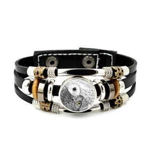 Dettaglio macro del bracciale in pelle multistrato nera con ciondolo civetta vintage