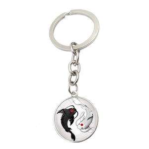 Macro shot of Yin Yang koi fish keychain with polished silver metal finish and glass dome