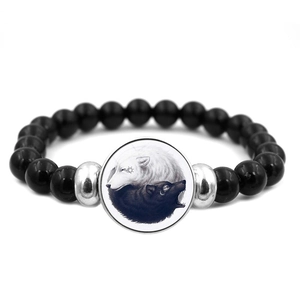 Macro detail of elastic beaded bracelet featuring black beads and dragon yin yang wolf charm