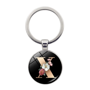 Detailed view of metal keychain with letter X and floral pattern under glass dome