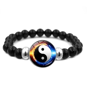 Detailed macro of black beaded bracelet with a fire and water yin yang tai chi pendant