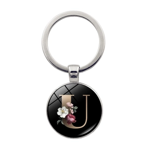 Macro detail of alphabet U keychain with vintage floral pattern and polished metal ring