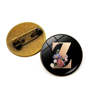Broche vintage en bronze avec lettre Z fleurie et épingle de sûreté sur fond blanc