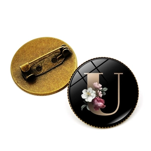 Détail de la broche lettre U avec motif floral et revers à épingle de sûreté en bronze