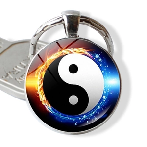 Detailopname van Tai Chi Yin Yang sleutelhanger met vuur en water glazen cabochon