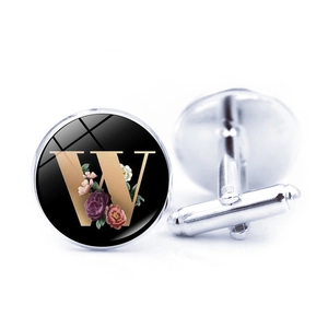Detail of silver cufflinks with golden letter W and floral design on black background