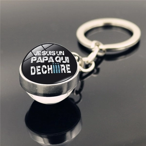 Détail du porte-clés en métal argenté avec dôme en verre et texte JE SUIS UN PAPA QUI DÉCHIRE