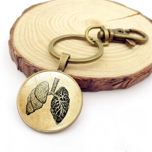 Vintage bronze anatomy keychain featuring a circular lung diagram pendant on wood