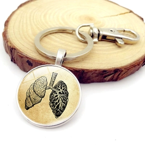 Vintage anatomical lung pendant keychain with silver metal ring on a rustic wood slice