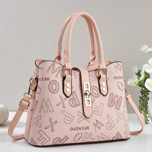 Hellrosa Shopper mit Buchstabendruck und goldener Schließe vor dezentem Dekor