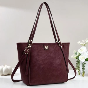 Détail d'un sac cabas bordeaux montrant la texture du cuir et le logo en métal