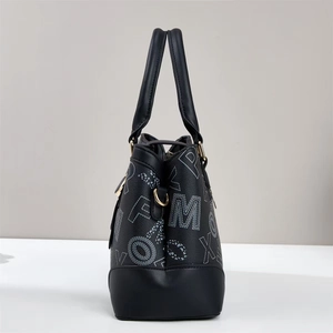 Detail of black tote bag with letter print, pebble texture leather and gold metal rings