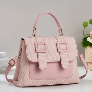 Rosa Schultertasche mit Webstruktur und dekorativen Schnallenriemen in einer Studioumgebung
