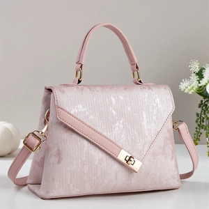 Détail d'un sac à main rose en tissu texturé avec fini métallisé et fermoir doré