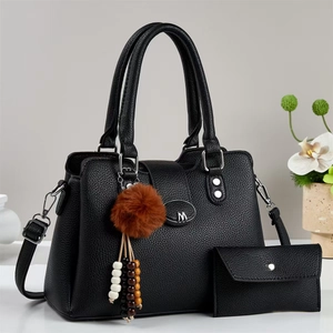 Détail du sac cabas noir grainé avec plaque argentée M et porte-clés pompon en fourrure