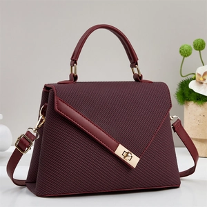 Close-up of deep wine red handbag featuring woven texture and gold metal clasp