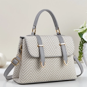 Detail of herringbone weave texture and grey leather straps on a beige handbag
