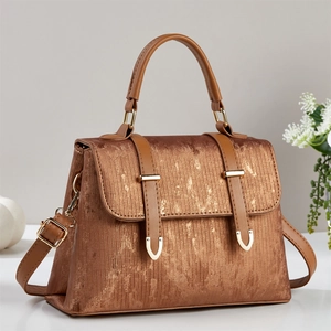 Brown tote bag with golden metallic texture and top handle in a minimalist setting