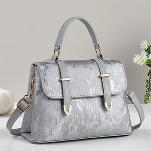 Detailed macro view of silver metallic textured fabric with golden hardware on a tote bag