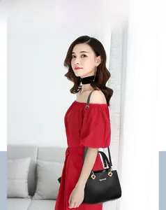 Fashionable black leather handbag with gold hardware styled on a model in a red dress