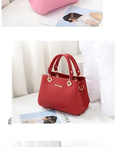 Detail of red and pink leather handbags with gold logo and stylish metal ring handles