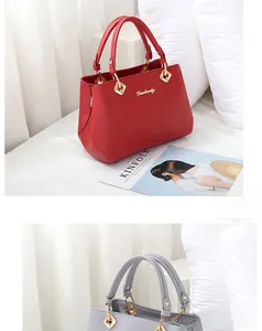 Detail view of red and grey lychee grain handbags with gold metal hardware and top handles