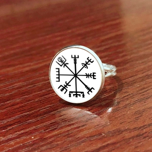 Detailaufnahme eines silbernen Wikinger-Kompass-Rings auf einem dunklen Holzhintergrund